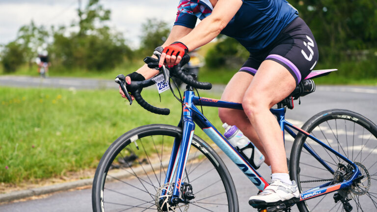 Torso of a woman rounding a steep switchback on her bike for neuromuscular training.