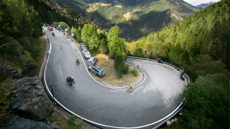 Wide shot of a cyclist rounding a paved mountain switchback