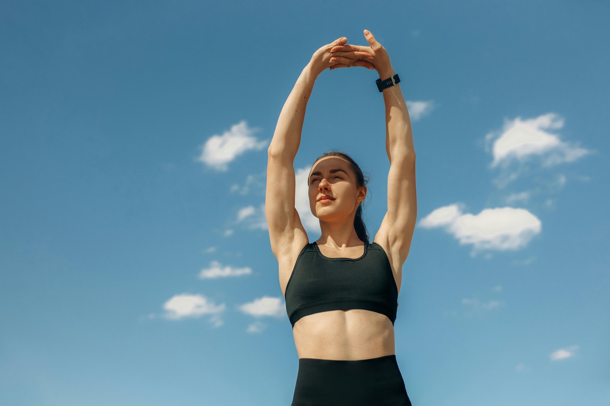 Woman stretching her arms in the sun for balancing sports and life