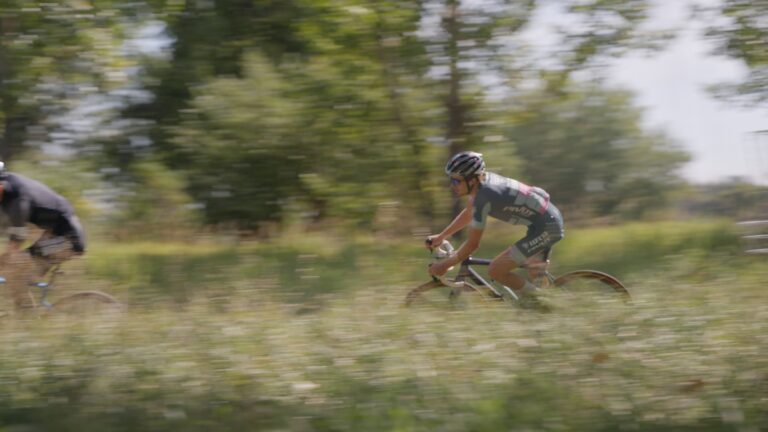 A cyclocross rider rounds a bend through tall grass for cycling thresholds