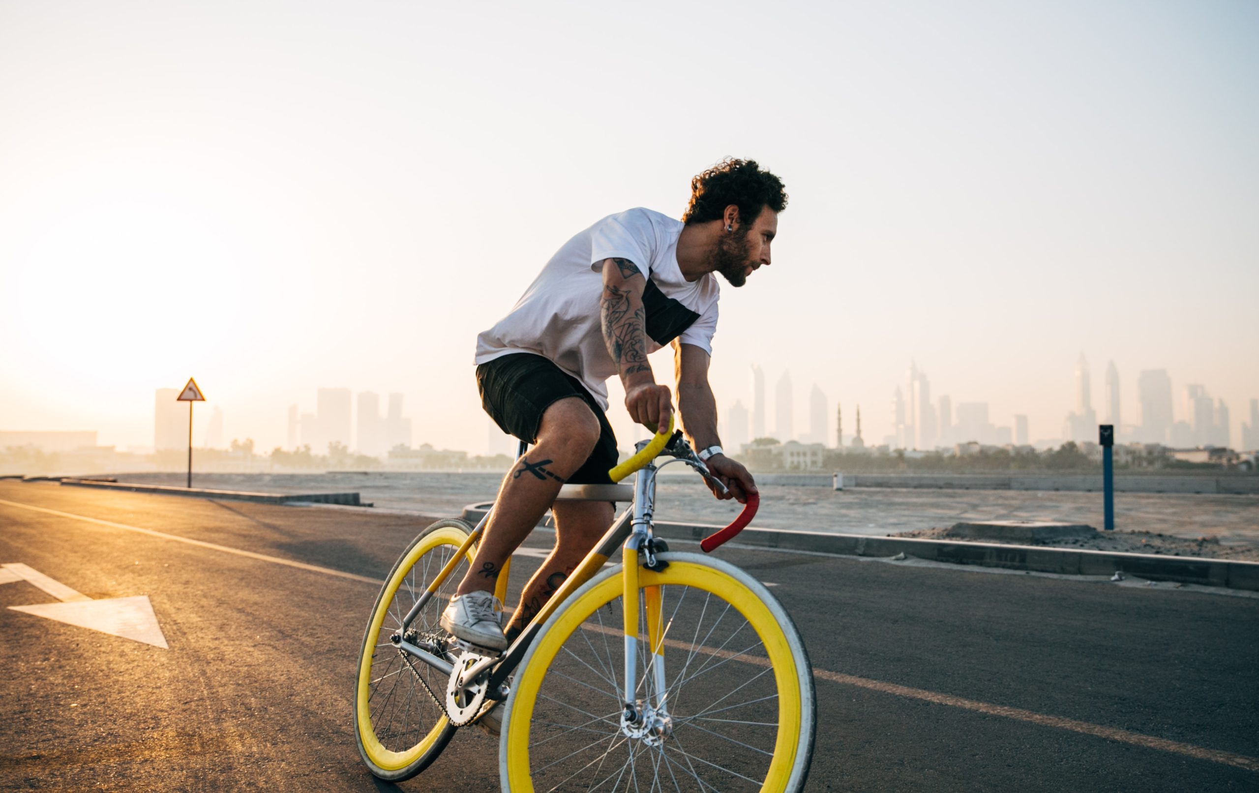 Casual rider riding on flatground in sunset with city in background