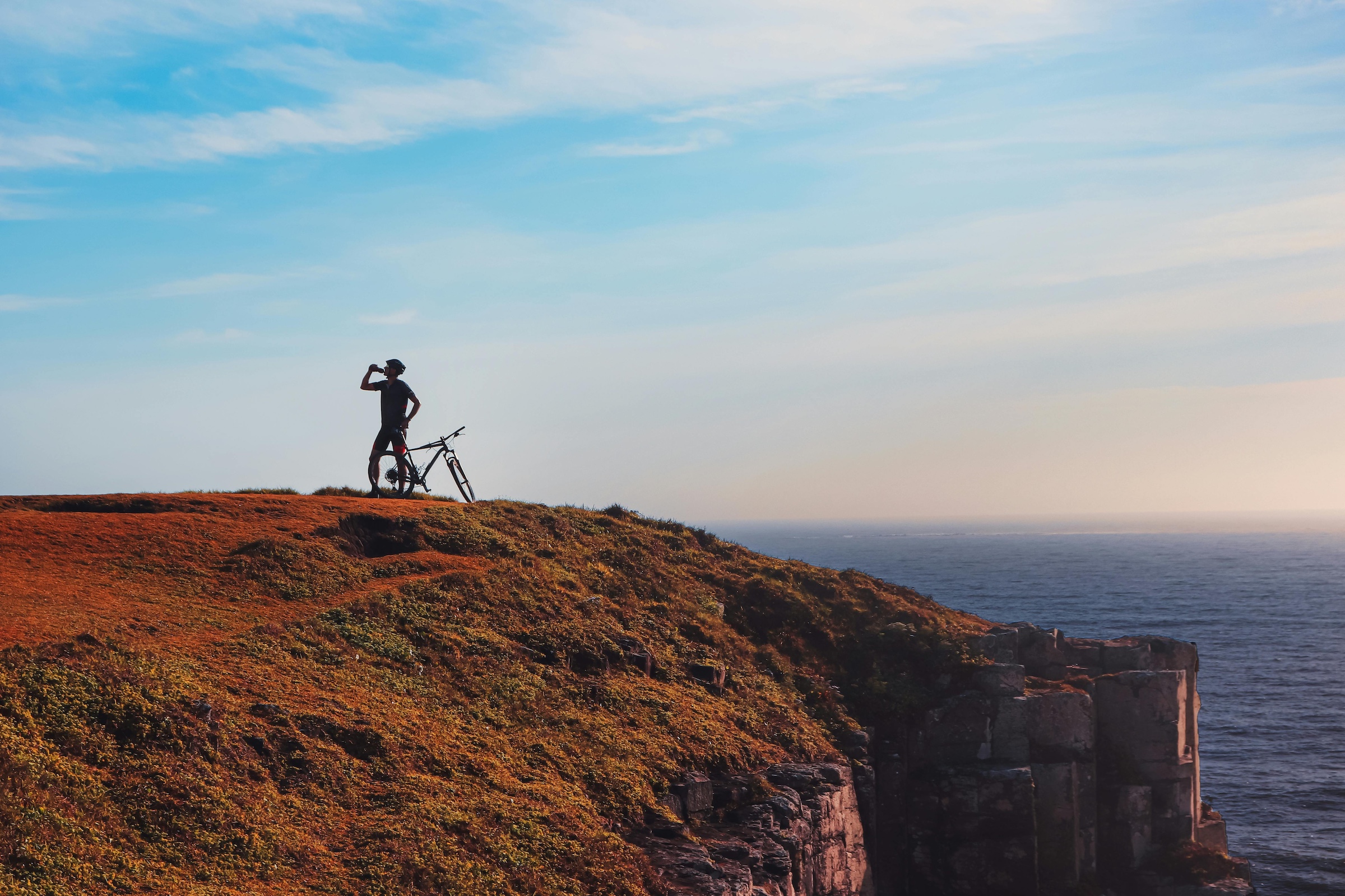 Cyclist resting at cliff edge for training in alignment