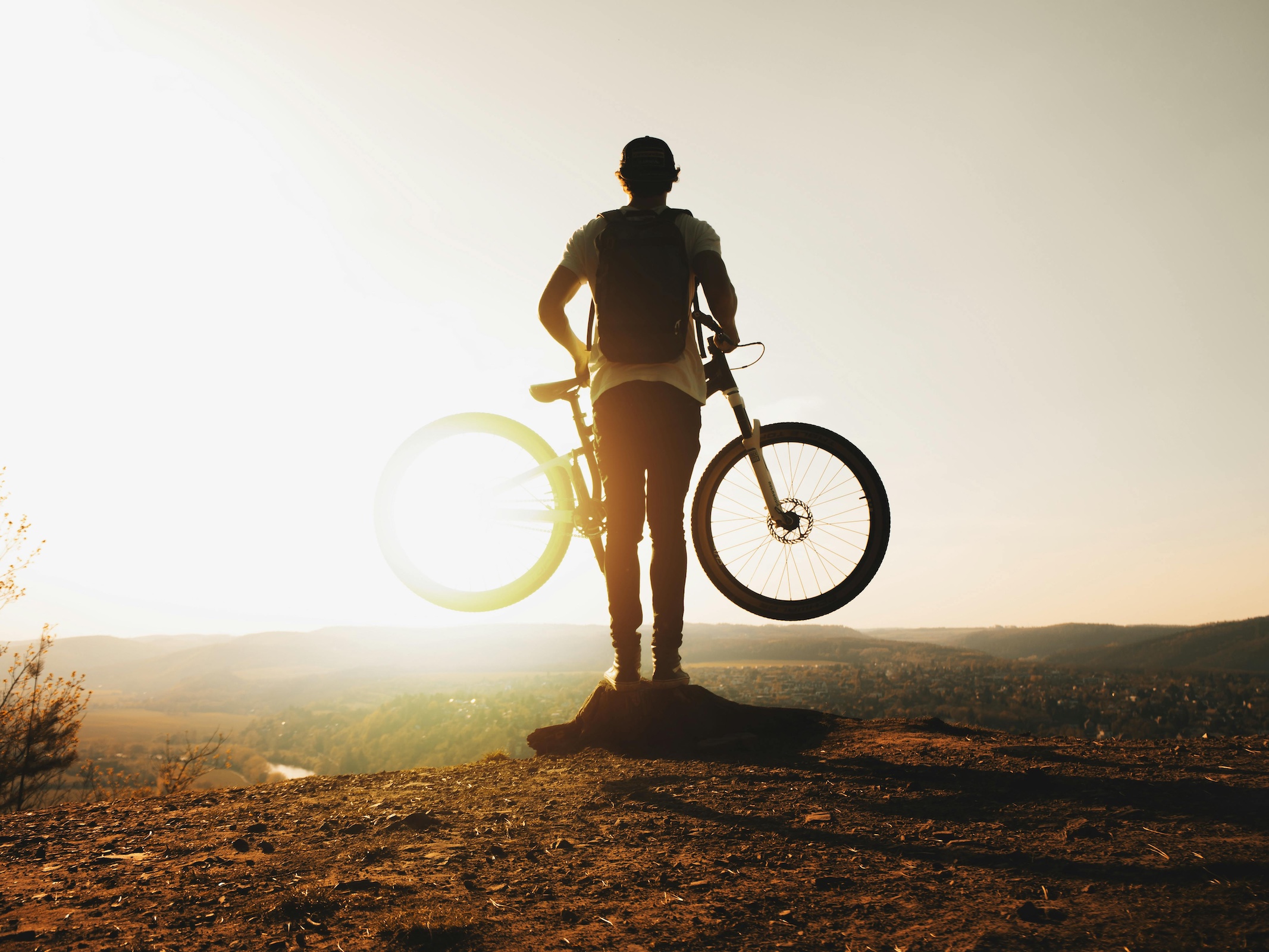Cyclist on rock edge in sunlight for reframing goal setting perspectives