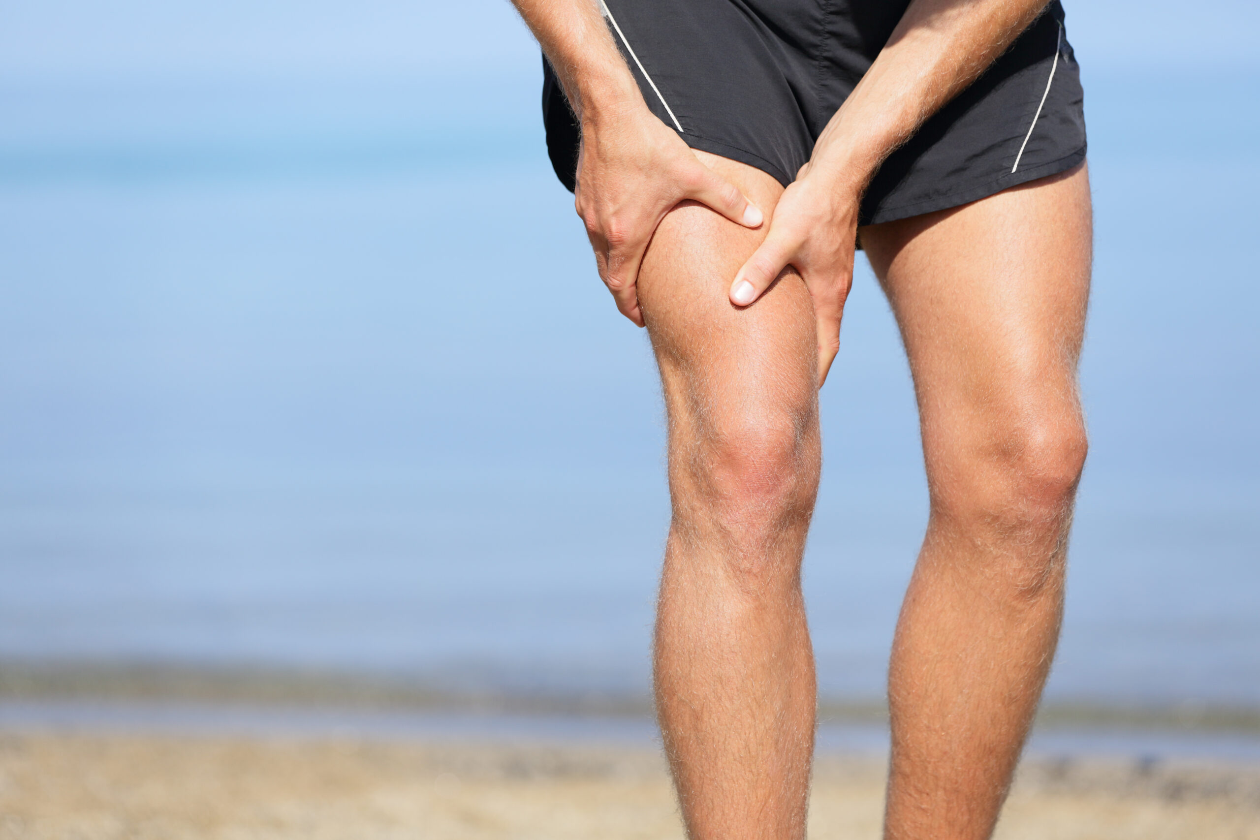 Runner Holding Leg Muscle Cramped on Beach