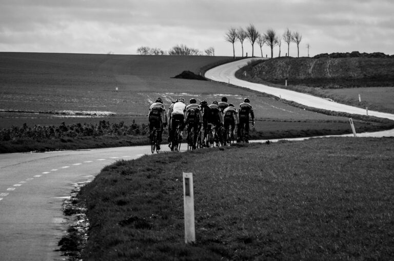 group of cyclists on winding road, black and white, stark landscape