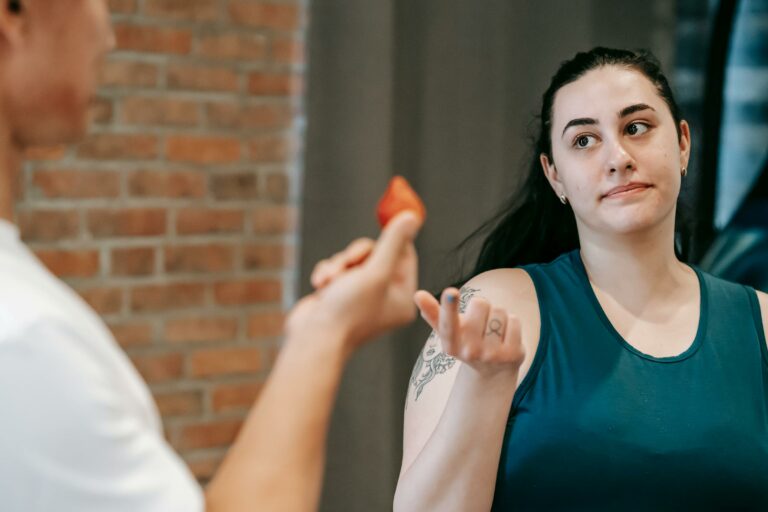 personal trainer offering a strawberry to a female athlete