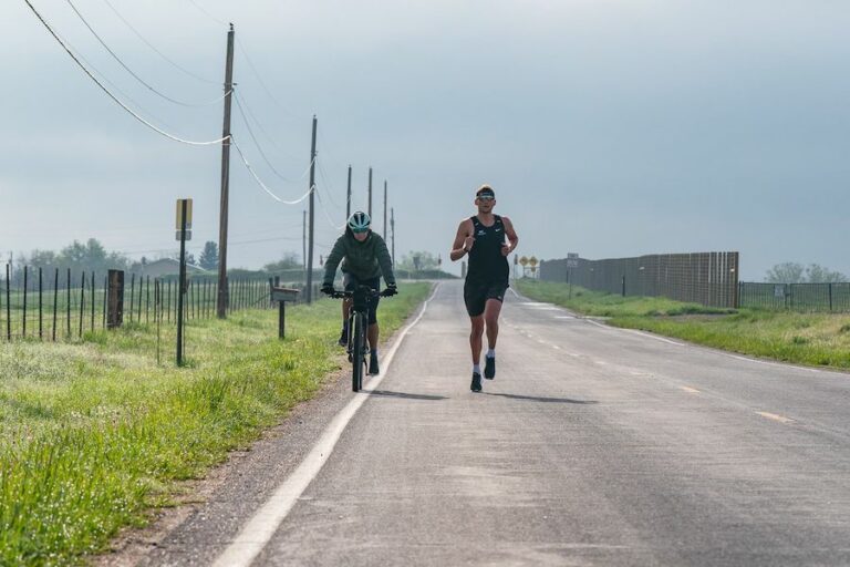 Julie Dibens riding alongside one of her athletes, pro triathlete Justin Metzler.
