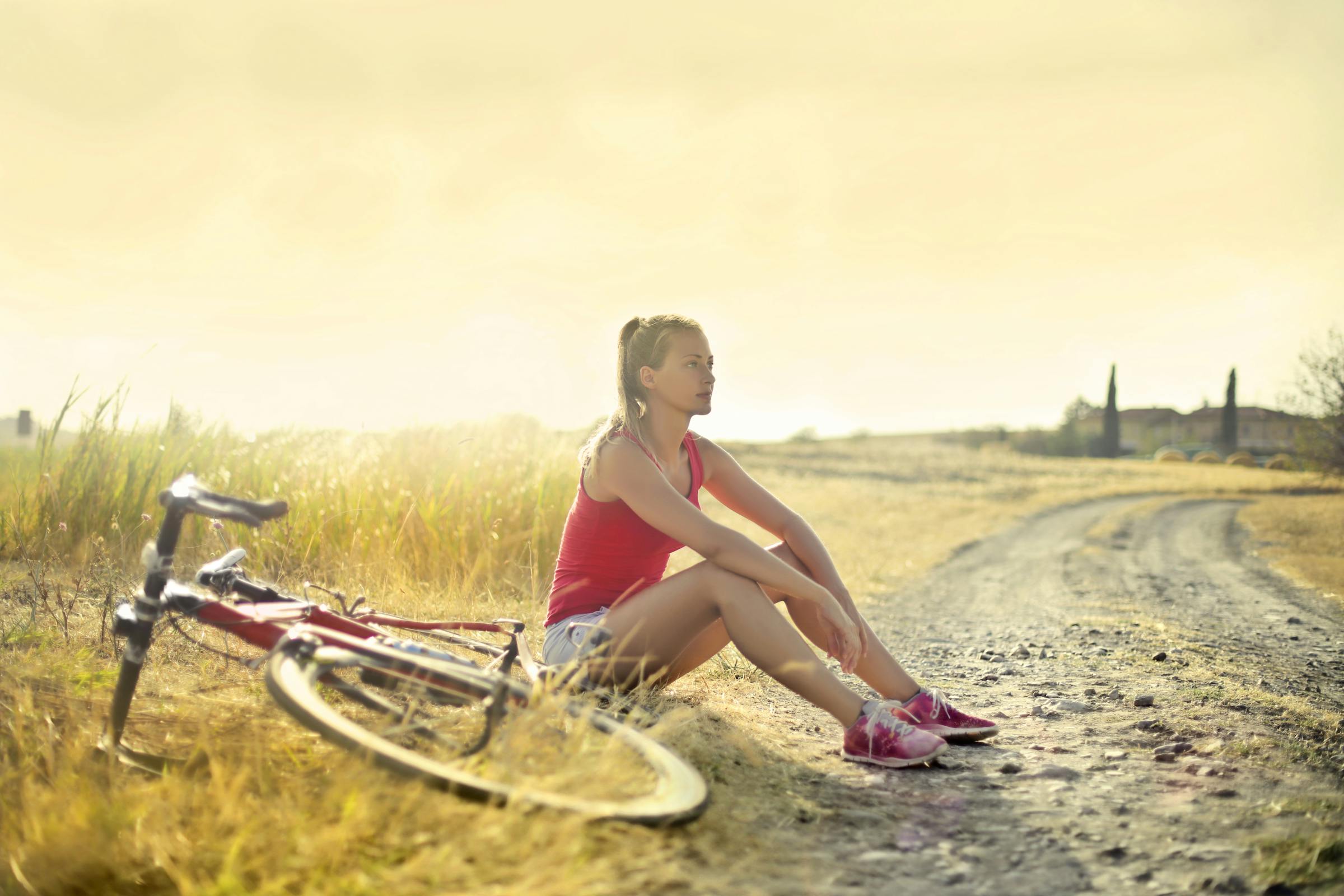 female cyclist sitting thoughtfully beside a road