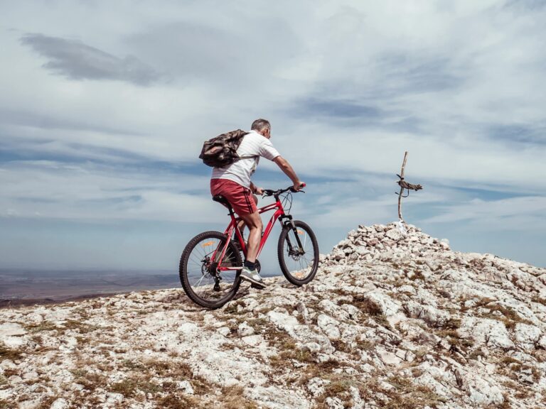older man reaching a mountain peak while mountain biking