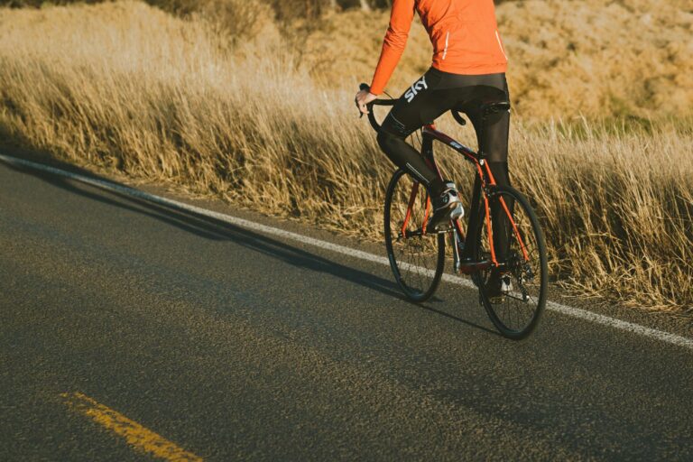 Man riding a bike on a road by a field