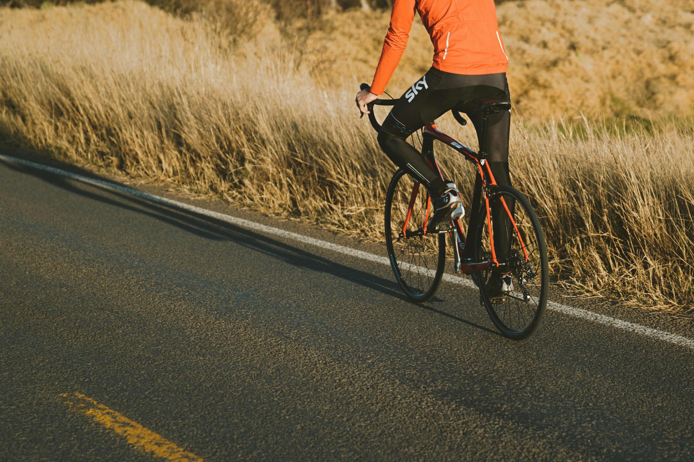 Man riding a bike on a road by a field