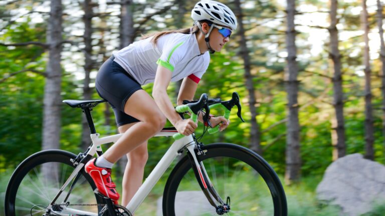 Female cyclist accelerating through a wooded road
