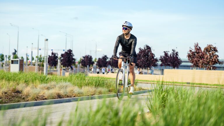 Male cyclist rides through a public park on a sunny day